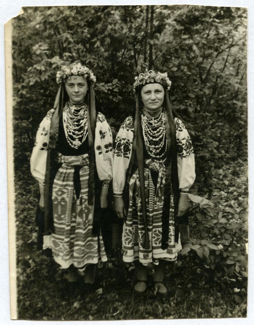 Photo. A bride wearing wedding attire standing with her bridesmaid